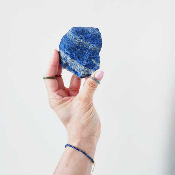 Mini 3mm lapis lazuli vermeil bracelet on wrist with raw lapis lazuli stone in hand.
